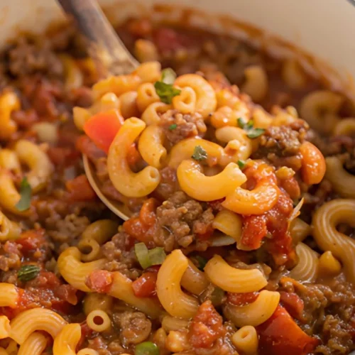Homemade American goulash recipe with tender elbow macaroni, seasoned ground beef, and rich tomato sauce in a white Dutch oven